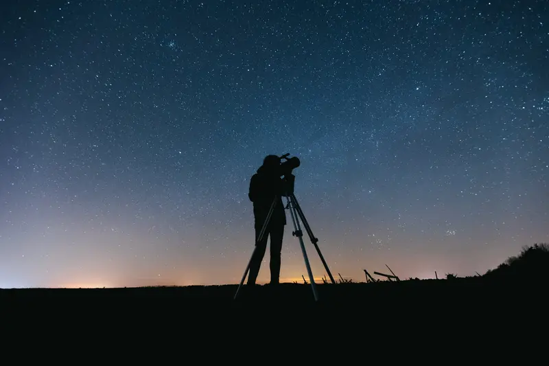 A ranch guest using a telescope to stargaze in the night sky